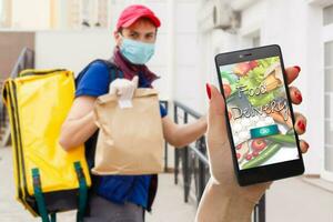 Lieferung Essen Bedienung beim heim. Mann Kurier geliefert das bestellen Nein Name Tasche mit Lebensmittel. Hand halten Clever Telefon mit Essen online Gerät auf Bildschirm foto