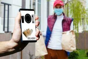 Lieferung Essen Bedienung beim heim. Mann Kurier geliefert das bestellen Nein Name Tasche mit Lebensmittel. Hand halten Clever Telefon mit Essen online Gerät auf Bildschirm foto