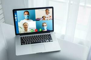 Nahansicht von Arzt haben Video Konferenz auf Laptop beim hölzern Schreibtisch foto