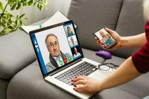 abgeschnitten Bild von jung Frau mit Laptop zum Video Konferenz beim Zuhause foto