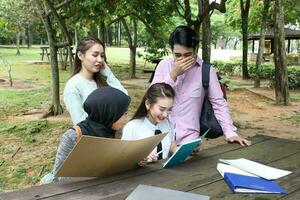 jung asiatisch malaiisch Chinesisch Mann Frau draussen Park Buch Datei Mappe Laptop Computer Telefon sitzen Stand Studie mischen foto