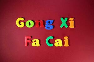 Plastik Alphabet Zeichen Beschriftung Gong xi Fa cai Chinesisch Neu Jahr auf kastanienbraun rot Papier Hintergrund foto