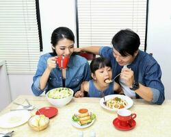 Süd Osten asiatisch Yong Familie Tochter Kind Elternteil Vater Mutter beim Essen Tabelle Essen Essen Mittagessen foto