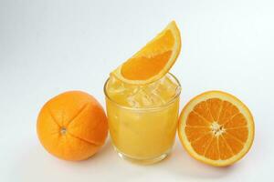 frisch Gelb Orange Saft im Glas mit ganze geschnitten Orange Obst und Eis Würfel auf Weiß Hintergrund foto