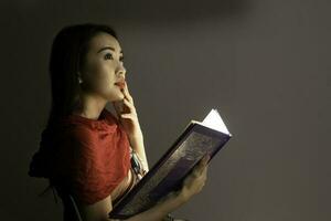 asiatisch Frau Öffnung Mystiker Buch Box magisch Licht dunkel Hintergrund foto