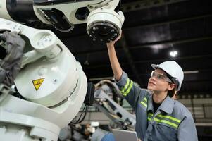 ein weiblich Ingenieur installiert ein Programm auf ein Robotik Arm im ein Roboter Lagerhaus. und Prüfung das Betrieb Vor Senden das Maschine zu das Kunde. foto