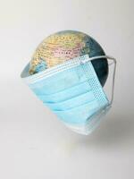 Globus Planet Welt Karte Erde tragen Gesicht Maske auf Weiß Hintergrund foto