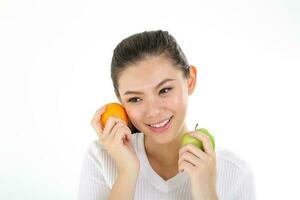 schön jung Süd Osten asiatisch Chinesisch Frau halten gesund Grün Apfel Orange auf Weiß Hintergrund foto