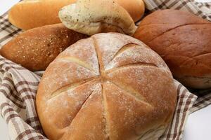 frisch gebacken Brot Laib Brötchen rollen runden lange mischen Wahrheit eingewickelt im kariert Küche Stoff Serviette Handtuch Über Weiß Hintergrund foto