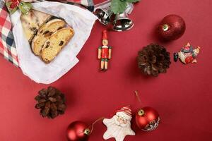 Weihnachten Weihnachten Dekoration Ornament Glocke Geschenk überprüft Stoff Stoff wickeln geschnitten Stollen Obst Kuchen Essen Kiefer Obst auf rot Hintergrund foto