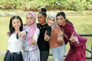 Gruppe von fünf Frau freunde malaiisch Chinesisch indisch asiatisch malaysisch draussen Grün Park See Natur zeigen Finger Nummer einer foto