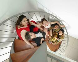 jung Süd-Ost asiatisch Frau Gruppe Sitzung auf Innen- Spiral- Treppe glücklich genießen Spaß aussehen Spaß oben Aussicht foto