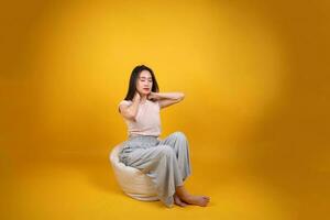 schön jung Süd Osten asiatisch Frau sitzt auf ein Weiß Sitzsack Sitz Orange Gelb Farbe Hintergrund Pose Mode Stil elegant Schönheit Stimmung Ausdruck sich ausruhen entspannen Übung strecken Yoga foto