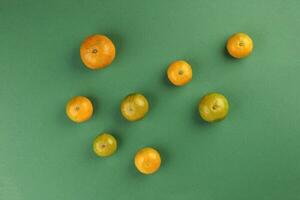 klein Gelb Grün Mandarin Orange auf Grün Farbe Papier Hintergrund Kopieren Raum zum Text foto