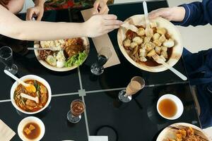 jung Süd-Ost asiatisch Frau Gruppe sich unterhalten feiern Essen genießen Essen Reis Curry Nudel Hähnchen trinken Prost auf Essen Tabelle oben Aussicht foto
