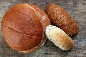 frisch gebacken Brot Laib Brötchen rollen runden lange mischen Wahrheit auf hölzern Über rustikal hölzern Hintergrund foto