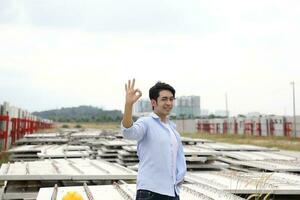asiatisch Mann malaiisch Arbeiter Ingenieur Verwaltung beim Konstruktion Seite? ˅ schwer Sicherheit Hut Helm in Ordnung Finger Zeichen foto