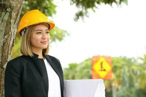 Frau malaiisch Chinesisch Arbeiter Ingenieur Verwaltung schwer Sicherheit Hut Helm beim Konstruktion Seite? ˅ Hand auf Hut glücklich Denken aussehen planen foto