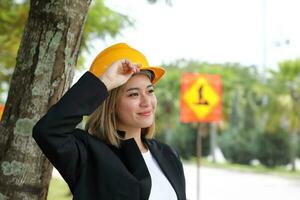 Frau malaiisch Chinesisch Arbeiter Ingenieur Verwaltung schwer Sicherheit Hut Helm beim Konstruktion Seite? ˅ Hand auf Hut glücklich Denken aussehen Zukunft foto