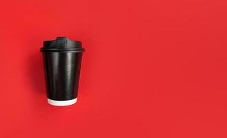 schwarze Papierkaffeetasse, zum auf rotem Hintergrund mit Kopienraum zu gehen foto