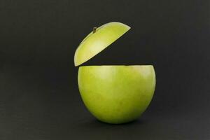 gesund Grün Schnitt Apfel schwebend oben Scheibe Saft trinken Idee Konzept auf schwarz Hintergrund foto