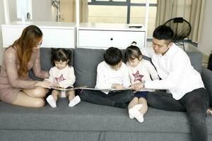 Eltern Kind Familie Vater Mutter Tochter Sohn sitzen auf Sofa lesen Schreiben Studie Lehren foto