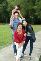 Süd-Ost asiatisch Mehrgenerationen Familie Eltern Tochter Oma Vater Mutter Kind Pose glücklich sitzen Stand draussen Park foto