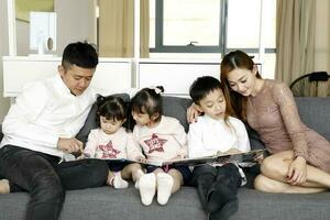 Eltern Kind Familie Vater Mutter Tochter Sohn sitzen auf Sofa lesen Schreiben Studie Lehren foto