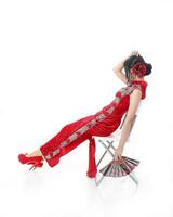 Süd Osten asiatisch Chinesisch Rennen ethnisch Ursprung Frau tragen rot Samt cheongsam mit Hand genäht Reihenfolge Arbeit Kleid Kostüm Hand Ventilator auf Weiß Hintergrund foto