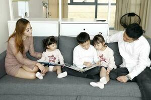 Eltern Kind Familie Vater Mutter Tochter Sohn sitzen auf Sofa lesen Schreiben Studie Lehren foto