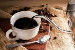 frisch Kaffee gießen das Kaffee in das Tasse. oder Kaffee Becher auf das hölzern Tabelle Espresso Mokka Cappuccino Barista foto