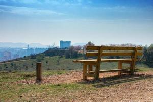 leere Holzbank im Frühlingspark über der Stadt foto