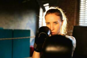 Frauen selbst Verteidigung Mädchen Leistung. stark Frau Kämpfer Stanzen mit Boxen Handschuhe zu Kamera. gesund stark Mädchen Stanzen Ausbildung Schläge suchen konzentriert gerade. passen Körper trainieren. foto