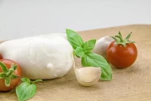 italienischer Bio-Mozzarella mit Kirschtomaten und Basilikum auf einem Schneidebrett foto