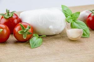 italienischer Bio-Mozzarella mit Kirschtomaten und Basilikum auf einem Schneidebrett