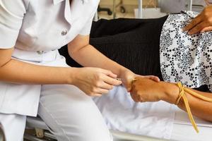 asiatische Krankenschwester injiziert an der Hand des Patienten für intravenöse Flüssigkeit foto