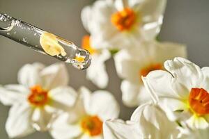 ein Pipette mit ein kosmetisch Produkt auf das Blume Hintergrund. foto