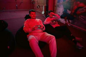 Vater und Sohn abspielen Gamepad Video Spiel Konsole im rot Spielen Zimmer. Papa und Kind Spieler. foto
