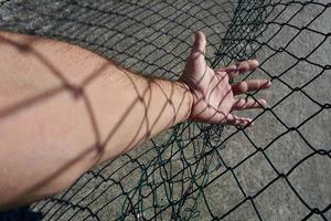 Hand erreicht einen metallischen Zaun foto