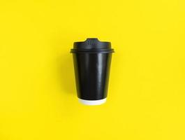 schwarze Papierkaffeetasse, zum auf gelbem Hintergrund zu gehen, legen Sie minimales Konzept auf Lager foto