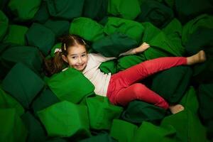 wenig Mädchen Kind Lügen auf Grün Sanft Würfel beim Spielplatz Park. Kind im aktiv Unterhaltungen. foto