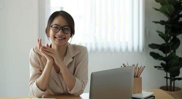 Porträt der lächelnden Geschäftsfrau, die am Schreibtisch im Büro sitzt und am Laptop arbeitet foto
