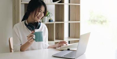 junge Frau, die Videoanruf auf Laptop-Computer zu Hause hat foto