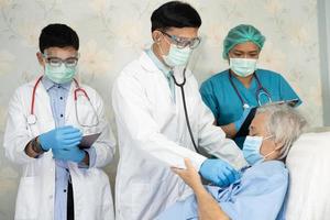 Das asiatische Ärzteteam überprüft die alte ältere Patientin auf Krankheit bis zur Motivation. Neue Normalität zur Behandlung der Infektion. Covid 19 Coronavirus auf der Krankenstation
