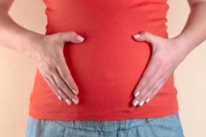 eine Nahaufnahme des Bauches einer schwangeren Frau in rot foto