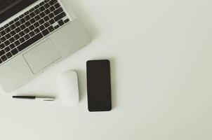 Laptop, Maus, Stift und Smartphone auf weißem Hintergrund