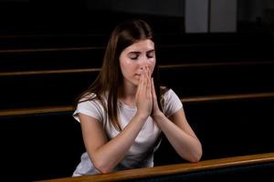 Ein christliches Mädchen im weißen Hemd betet mit demütigem Herzen in der Kirche foto