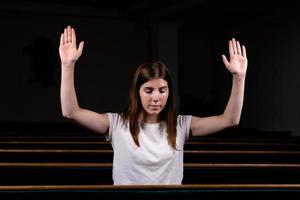 Ein christliches Mädchen im weißen Hemd betet mit demütigem Herzen in der Kirche foto