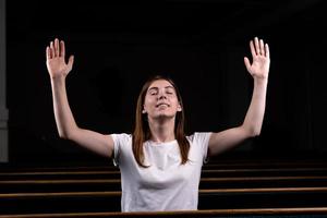 Ein christliches Mädchen im weißen Hemd betet mit demütigem Herzen in der Kirche foto