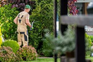 Garten Arbeiter Trimmen Pflanzen während Frühling saisonal Instandhaltung foto